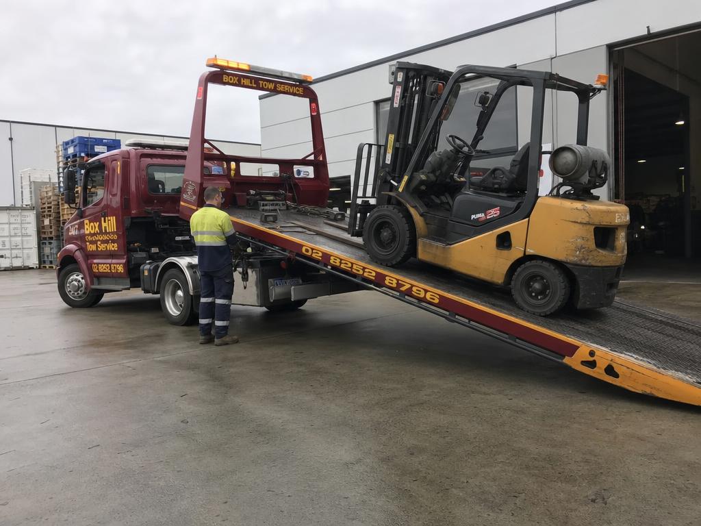 Forklift being loaded onto a Box Hill Tow Service heavy flatbed truck